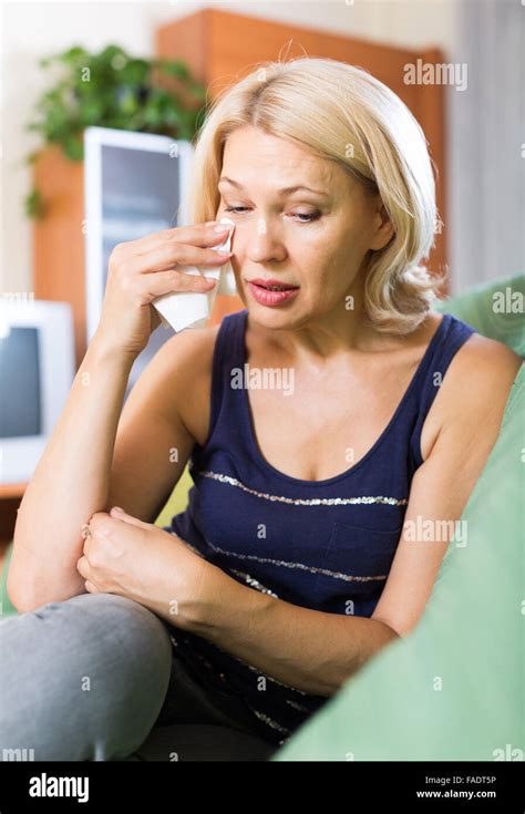 Sad And Lonely Mature Woman 60 Years Old Sitting On Couch At Home Stock