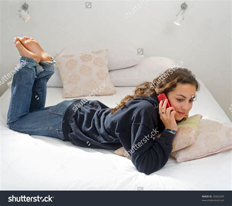 David prado / addictive creative; Teenager Girl Lying In Bed Using Her Cell Phone Стоковые ...