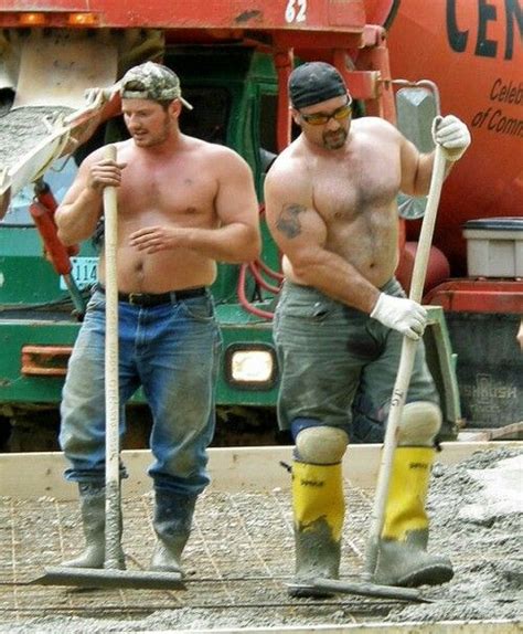 Two Men With Shovels And Work Boots Are Standing In Front Of A Construction Site