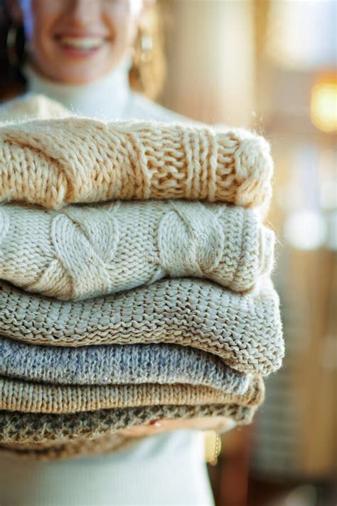 Closeup On Happy Young Woman Holding Pile Of Sweaters Stock Photo