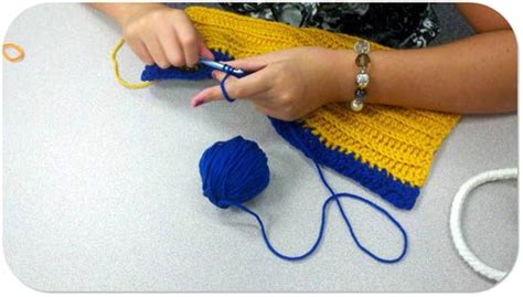A Woman Is Knitting With Blue Yarn On The Table Next To Some Balls Of Yarn