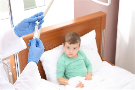 Doctor Adjusting Intravenous Drip For Little Child In Hospital Stock