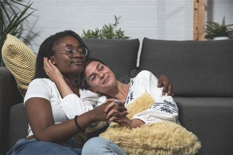 Two Young Mixed Race Lesbian Couple Black African And White Woman Sitting In Their Apartment And