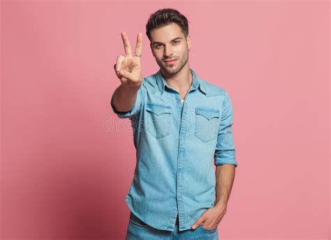 Casual Man Makes Peace Sign While Holding His Pocket Stock Photo