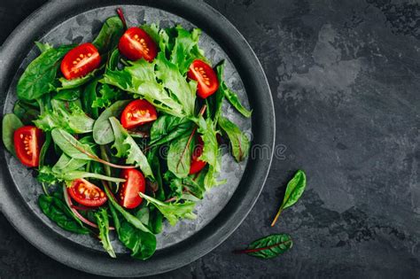 Fresh Green Mixed Lettuce Salad Bowl With Tomato On Dark Background