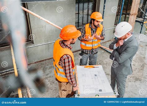 High Angle View Of Confused Builders And Architect Discussing Building