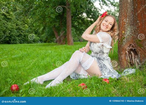 Young Fashionable Girl In White Summer Dress And Lace Stockings Sitting