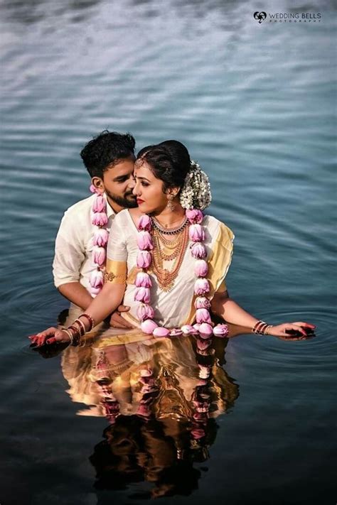 A Man And Woman Sitting In The Water With Garlands Around Their Necks
