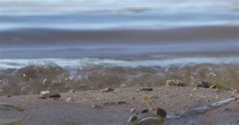 A Blurry Photo Of The Beach And Ocean Waves With Small Rocks In The