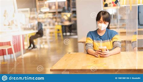 The Asian Woman Holding The Cup Of Coffee Wearing Surgical Mask Sitting