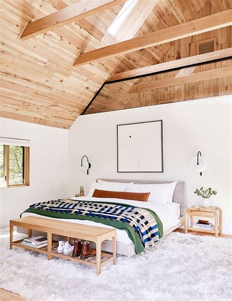 A Bedroom With White Walls And Wood Ceilinging Has A Large Bed In The