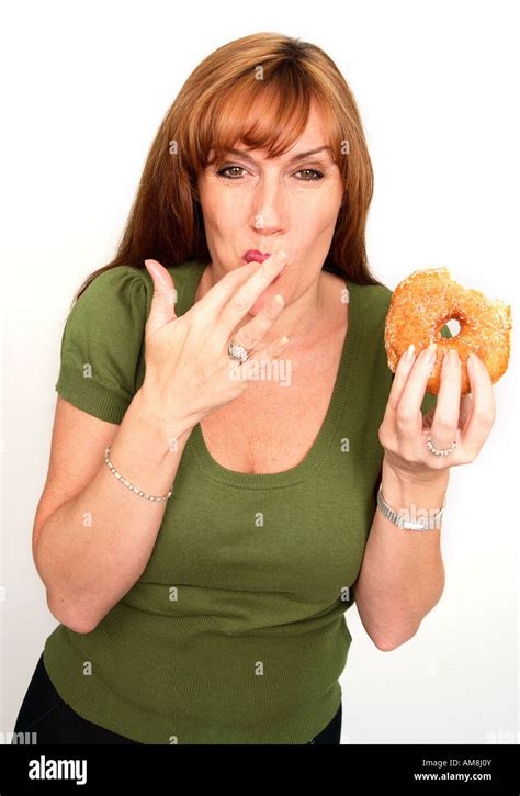 Cut Out Of An Smiling Woman Licking The Sugar Off Her Finger While Holding A Doughnut Stock