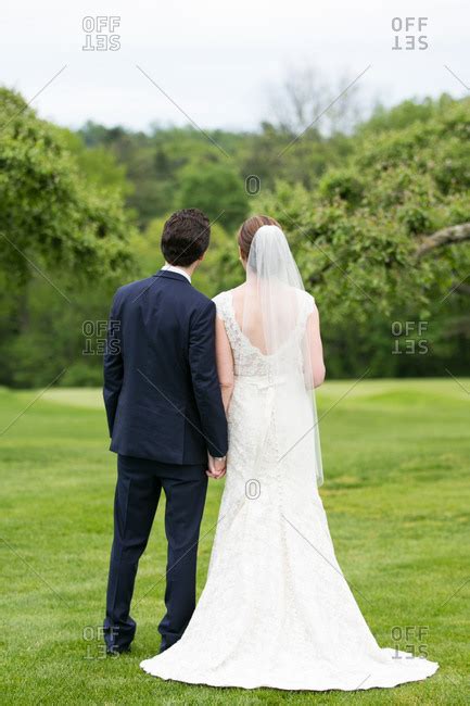 Rear View Of A Bride And Groom Standing Together On A Lawn Stock Photo