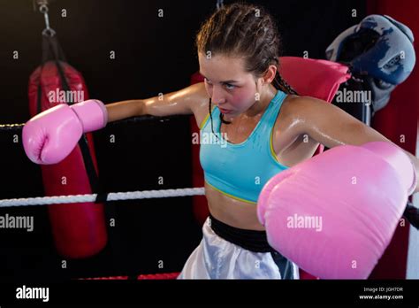 Young Female Boxer Sitting In Corner Of Boxing Ring At Fitness Studio