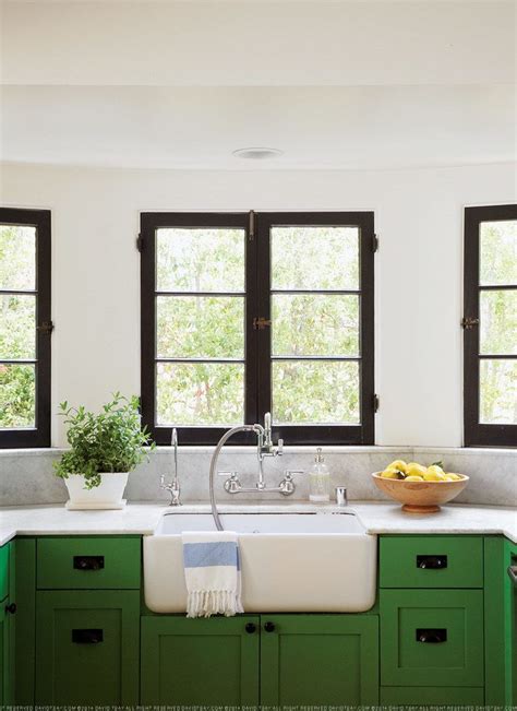 After filling in all the holes around the window with sheetrock mud, just like last time. green kitchen cabinets, black window trim, white walls ...