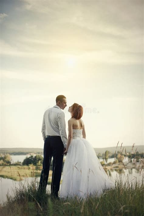 Wedding Couple Sitting On Bridge Near Lake On Sunset At Wedding Day Bride And Groom In Love
