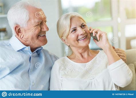 Senior Couple Talking On Mobile Phone At Home Stock Photo Image Of