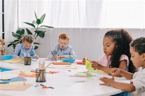 Multicultural Preschoolers Drawing Pictures With Pencils In Classroom