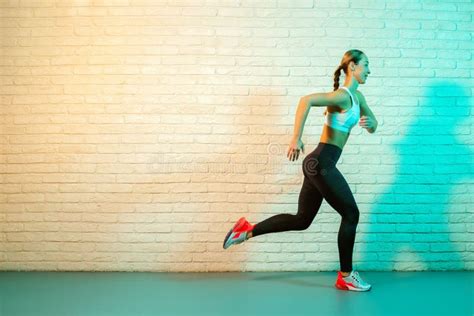 Sporty Young Attractive Woman Jogging Front Brick Wall In Neon Lights