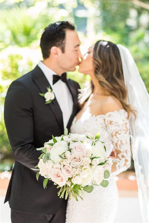 A Bride And Groom Kissing In Front Of Trees