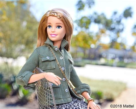 a barbie doll is holding a purse and posing for the camera