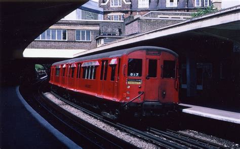 A Red Train Traveling Down Tracks Next To A Tall Building With Lots Of