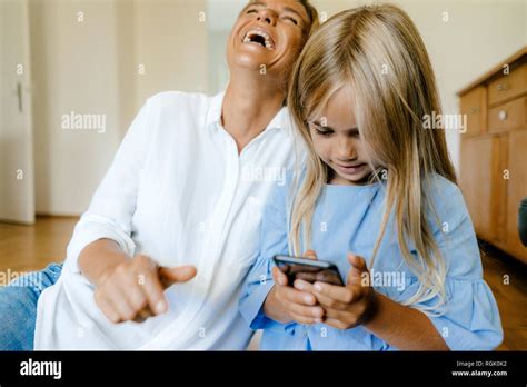 Riendo Madre E Hija Mirando El Smartphone Fotografía De Stock Alamy