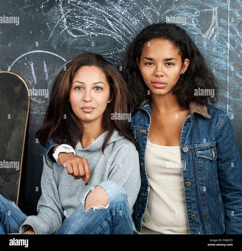 Two Mulatto Girlfriends Teenage In Classroom Hugging At Blackboard Back To School Concept Stock