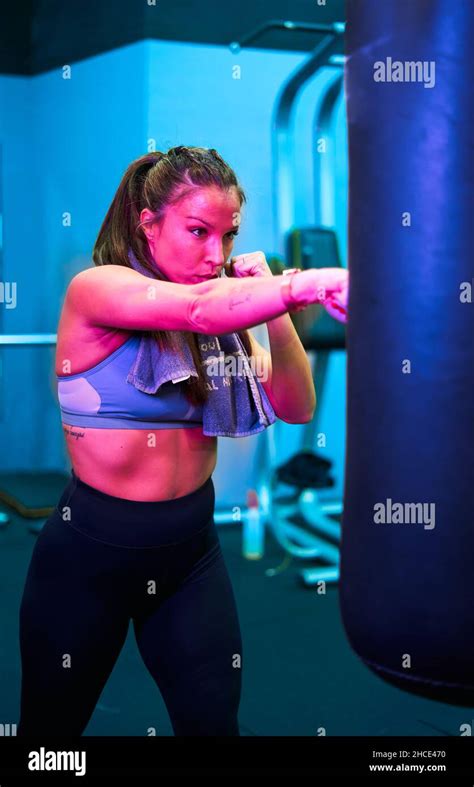 Strong Ethnic Female Boxer Punching Boxing Bag While Training In Modern