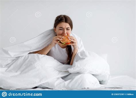 Hungry Young Female Greedily Eating Burger On Bed Eating Disorder Consolation With Overeating