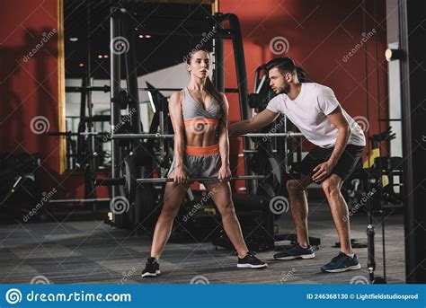 Handsome Trainer Supporting Attractive Sportswoman Lifting Stock Photo