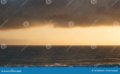 Moody Sunrise Shot With Calm Ocean And Thick Cloud Layer In Upper Third