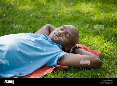 A Young African Man Sleeping On The Grass In A Park Stock Photo Alamy