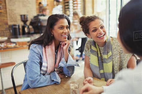 Smiling women friends talking at cafe table - Stock Photo - Dissolve