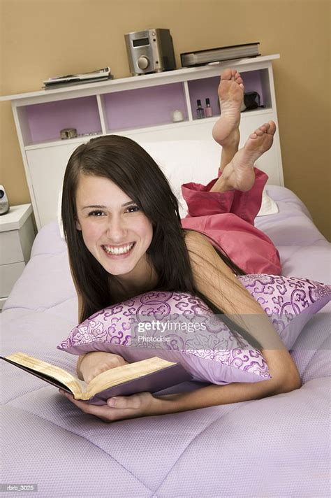Portrait Of A Young Woman Lying On A Bed Holding A Book ストックフォト Getty