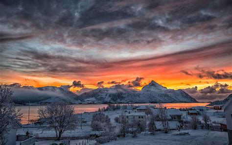 Northern Norway Winter Snow Mountains With Rural Houses And Red Sky
