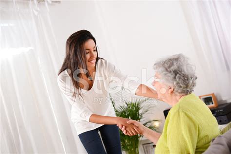 Cheerful Young Girl Taking Care Of Elderly Woman At Home Stock Photo