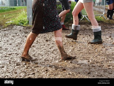 A Barefoot Female Festival Goer Walks Through Mud After Heavy Rainfall