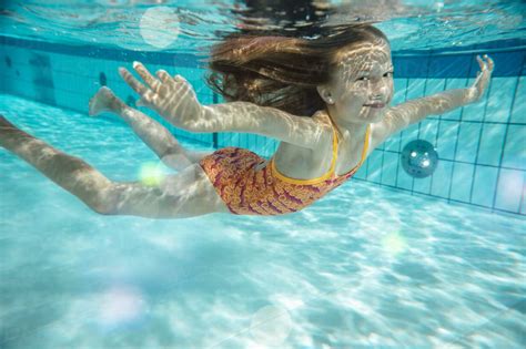 porträt eines lächelnden mädchens das im schwimmbad unter wasser schwimmt lizenzfreies stockfoto