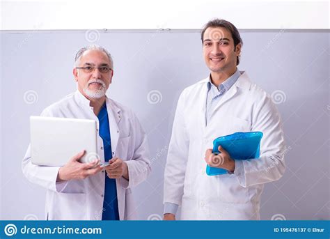 Experienced Doctor Teaching Young Male Assistant Using Computer Stock