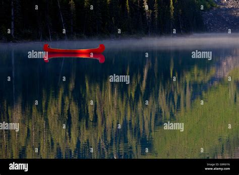 Red Canoe Anchored On Lake Louise With Rocky Mountains Reflection
