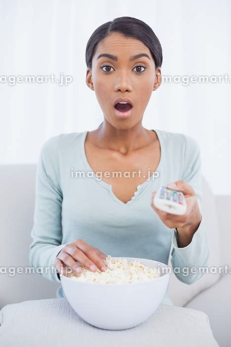 Surprised Attractive Woman Sitting On Cosy Sofa Eating Popcorn While Watching Tvの写真素材 31684506