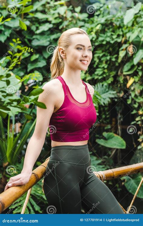 Beautiful Young Woman In Sportswear Leaning Back On Fence Stock Photo