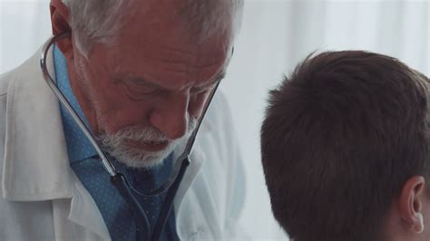 Senior Doctor Examining A Small Boy In His Office Stock Video Footage