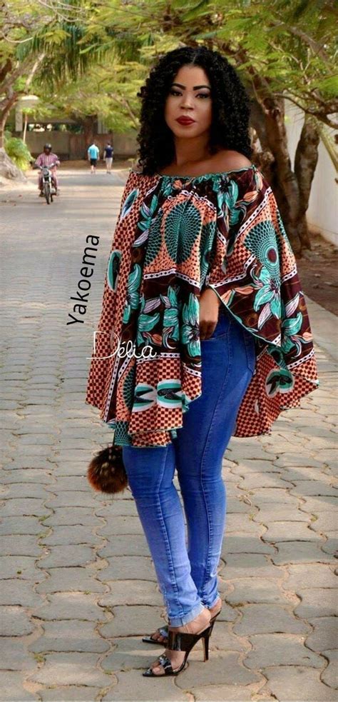 a woman standing on a brick road wearing a top with an african print and blue jeans