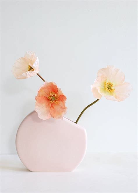 Two Pink Flowers In A White Vase With The Word Floral On It S Side