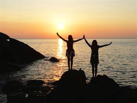 Two Silhouette Girls Standing At The Rocky Seaside On Sunset Stock Image Image Of People