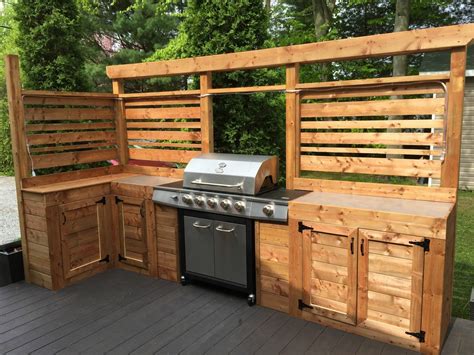 An Outdoor Kitchen Made Out Of Wood With Grill And Cabinets On The