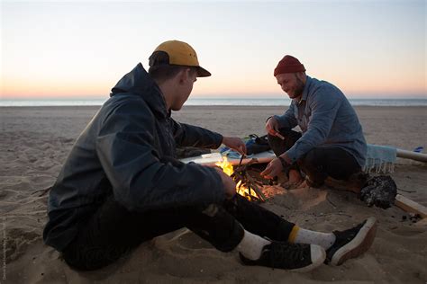 Cold Night Two Friends Making A Bonfire On The Beach During Sunset