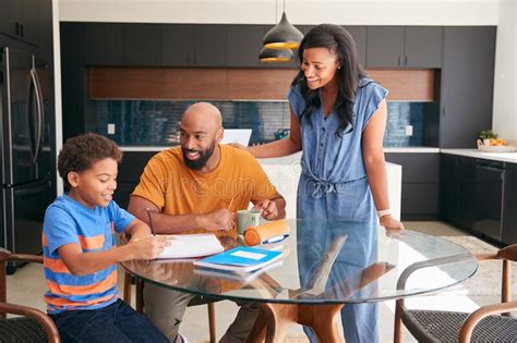 African American Parents Helping Son Studying Homework In Kitchen Stock